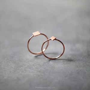May include: Two thin copper-toned rings, each featuring a small, flat square-shaped accent at the top. The rings have a smooth, metallic finish and a delicate, circular band design. The text "TheHeavenOfCraft" is visible at the bottom of the image.