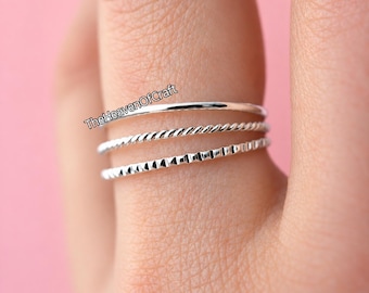 May include: A set of three thin silver rings stacked together. The top ring is smooth, the middle ring features a twisted rope texture, and the bottom ring has a notched, geometric pattern. The text TheHeavenOfCraft is visible on the rings.