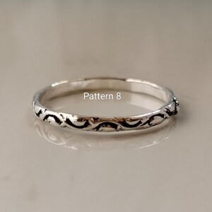May include: A thin silver ring featuring a continuous embossed scroll pattern along the outer band. The metal has a polished finish with darkened recessed areas to highlight the design. The text Pattern 8 is visible above the ring.