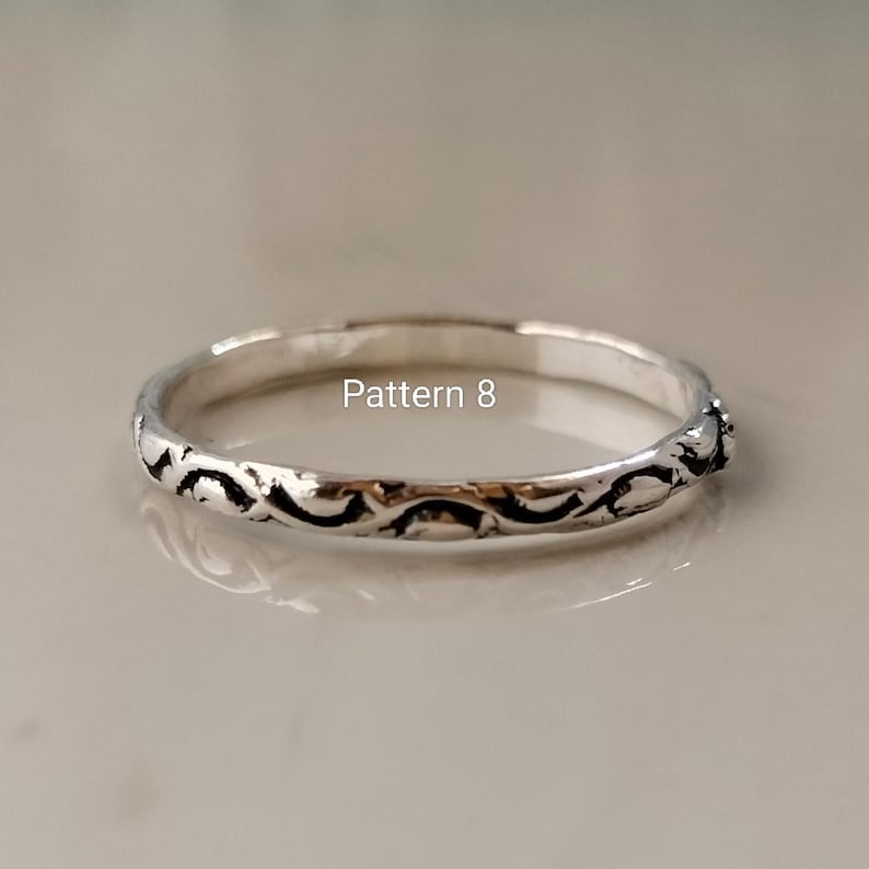 May include: A thin silver ring featuring a continuous embossed scroll pattern along the outer band. The metal has a polished finish with darkened recessed areas to highlight the design. The text Pattern 8 is visible above the ring.