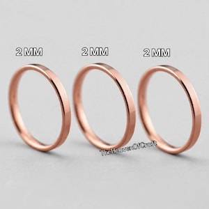 May include: Three rose gold-colored rings with a smooth, flat surface. Each ring is labeled with the text 2 MM above it. The text TheHeavenOfCraft is visible near the bottom right ring. The rings have a simple, circular band design.