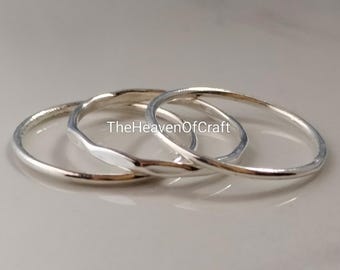 May include: Three thin silver-coloured metal rings arranged in an overlapping stack. The rings have a smooth, polished finish and a rounded profile. The text TheHeavenOfCraft is printed in the centre of the rings in a clear, dark font.
