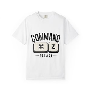 Puede incluir: Camiseta blanca con un diseño gráfico. El diseño presenta las palabras "COMMAND PLEASE" sobre dos teclas de teclado. Las teclas muestran el símbolo Comando y la letra "Z". El diseño es en negro y blanquecino.
