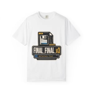 Puede incluir: Camiseta blanca con un diseño gráfico que presenta el texto "FINAL_FINAL_v3" y un icono de disquete. El diseño también incluye las palabras "definitely final". La camiseta está hecha de un material suave.