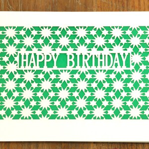 May include: White card with a green geometric pattern cut out to reveal the words "Happy Birthday".