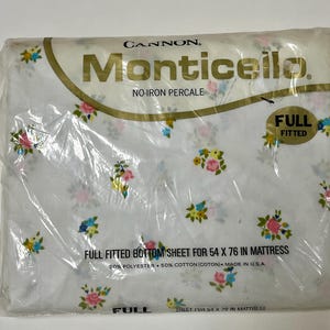 May include: A Cannon Monticello no-iron percale full fitted bottom sheet in white with a floral pattern of pink roses and blue and yellow flowers. The packaging states it is for a 54 x 76 inch mattress and is made of 50% polyester and 50% cotton.
