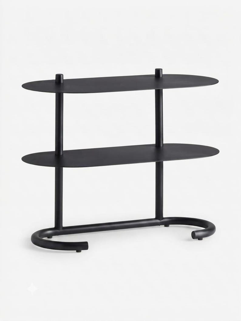 May include: A matte black metal shelving unit featuring two oval-shaped shelves supported by two vertical poles. The base consists of a curved, U-shaped tubular frame that provides stability, creating a clean and functional storage structure.