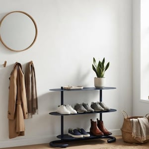 May include: A dark blue three-tiered oval shoe rack with a flat top surface holding a small white tray and a potted snake plant. The rack displays various pairs of trainers, slip-ons, and leather boots on its shelves, supported by a curved base.
