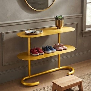 May include: A two-tier gold metal console table with oval shelves, featuring a small succulent in a gold pot and a shallow dish with keys on the top shelf, and three pairs of children's shoes on the bottom shelf, positioned near a wooden stool.