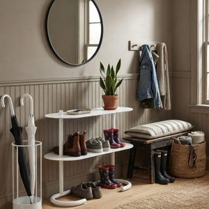 May include: A white two-tier oval console table holding a potted snake plant, brown leather boots, and grey trainers. Beside it, a white cylindrical umbrella stand holds two umbrellas, and a dark wooden bench features a striped cushion.