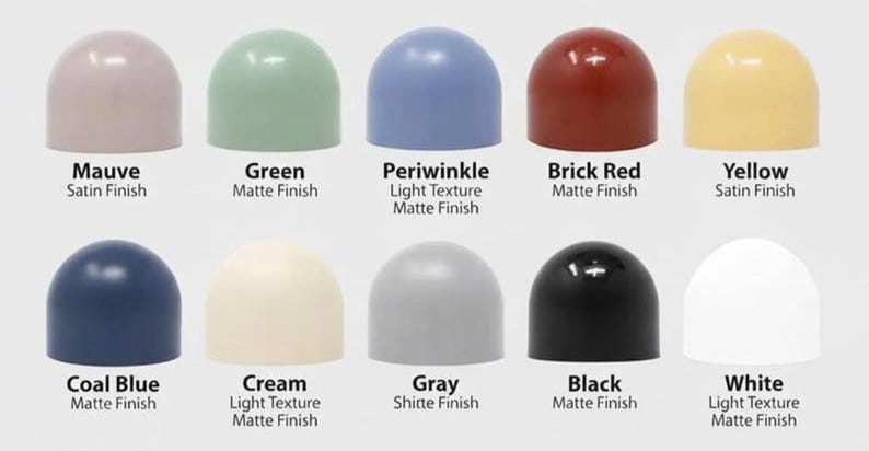 May include: Ten dome-shaped objects arranged in two rows, labelled with colours and finishes: Mauve satin, Green matte, Periwinkle light texture matte, Brick Red matte, Yellow satin, Coal Blue matte, Cream light texture matte, Gray matte, Black matte, and White light texture matte.