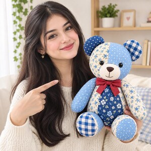 May include: A stuffed teddy bear crafted from patchwork fabric in various shades of blue and white. The bear features floral, polka dot, and gingham patterns, black button eyes, a stitched nose and mouth, and a solid dark red fabric bow tie.