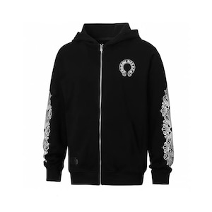 Puede incluir: Una sudadera negra con cremallera, un logotipo de herradura blanco en el pecho izquierdo y complejos patrones de volutas florales blancas en ambas mangas. La prenda incluye una cremallera metálica de color plateado y una capucha.