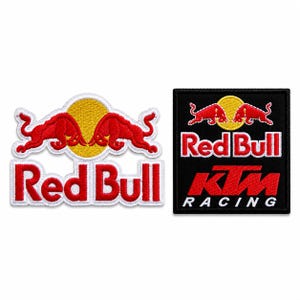 Op de afbeelding: Twee geborduurde patches. De linker patch toont het rode en gele Red Bull logo met twee stieren die tegenover elkaar staan. De rechter patch is een zwart vierkant met het Red Bull logo boven het rode KTM logo en het woord RACING in wit.