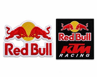 Puede incluir: Dos parches bordados. El parche izquierdo muestra el logotipo de Red Bull con dos toros rojos frente a frente sobre un sol amarillo y el texto Red Bull en rojo. El parche derecho es un cuadrado negro con el logotipo de Red Bull, el texto Red Bull y KTM Racing.