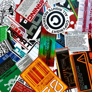 Pode incluir: Uma coleção de autocolantes retangulares e circulares variados com temas industriais, de aviso e técnicos. Os autocolantes apresentam várias cores, incluindo laranja, vermelho, verde e preto, com textos como WARNING, DIGITAL HEART, ALL RIGHTS RESERVED, EXTREME HIGH VOLTAGE e ARRAY INDUSTRY.