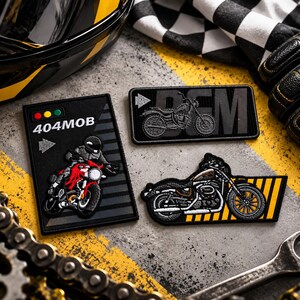 Pode incluir: Três emblemas bordados com temas de motocicletas. Um emblema retangular mostra um condutor numa moto vermelha com o texto 404MOB. Outro emblema retangular exibe a silhueta de uma moto com as letras BCM. Um terceiro emblema tem a forma de uma moto.