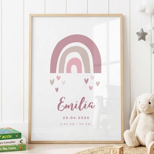 May include: A framed wall print featuring a muted pink and beige rainbow graphic with small hearts below. The text reads Emilia, 23.04.2026, and 3.56 kg / 49 cm. The print is housed in a light wood frame, displaying birth details in a clean font.