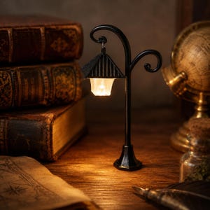 May include: A miniature black street lamp with a curved post and a hanging lantern shade that emits a warm, glowing light. The lamp features a dark, ridged roof design and a clear, translucent base that illuminates the surrounding area.