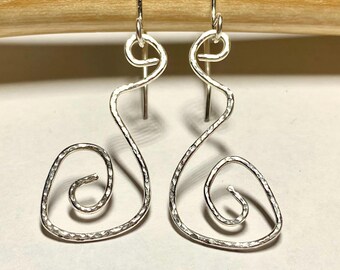 May include: A pair of silver-toned, hammered-metal earrings. Each earring features a spiral design at the bottom and a curved, elongated shape leading to a hook at the top. The earrings are displayed against a light background.