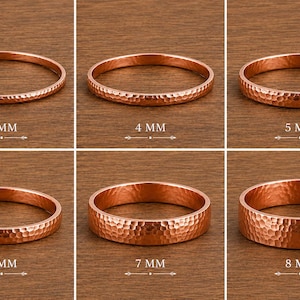 May include: Six copper rings with a hammered texture arranged in a grid. Each ring is labeled with its width, ranging from 3 mm to 8 mm. The rings are displayed in increasing order of thickness, showcasing the consistent metallic finish and pattern.