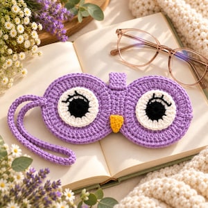 May include: A purple crochet sleep mask shaped like an owl with large white and black eyes, long black eyelashes, and a small yellow beak. The mask features a matching purple crochet strap and is designed to cover the eyes for rest and relaxation.