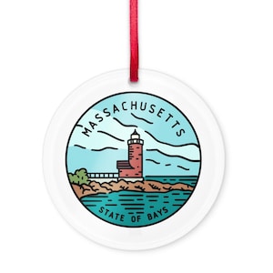 May include: White ceramic ornament with a red lighthouse illustration on a blue background. The text "MASSACHUSETTS STATE OF BAYS" is printed around the lighthouse.
