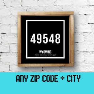 Może przedstawiać: Czarno-biały znak z drewnianą ramą. Znak ma biały kwadrat z kodem pocztowym "49548" i tekstem "WYOMING Kent County, Michigan".