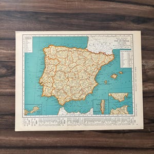 May include: A vintage map of Spain and Portugal, featuring detailed geographical information. The map has a light blue ocean background with landmasses in shades of yellow and brown. Text includes "Spain and Portugal" and various place names.