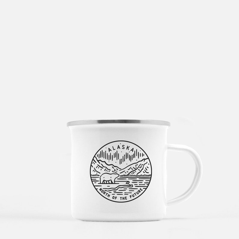 Puede incluir: Taza de camping de esmalte blanco con un gr&aacute;fico en blanco y negro de un oso, monta&ntilde;as y la aurora boreal. El gr&aacute;fico est&aacute; en un c&iacute;rculo con el texto "Alaska North of the Future".
