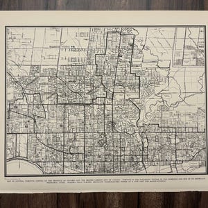 May include: A vintage black and white map of Toronto, Canada, from the World Atlas and Gazetteer. The map details the city's layout, including streets, neighborhoods, and geographical features. Text at the bottom describes Toronto as the building center of the St. Lawrence and one of its industrial cities.