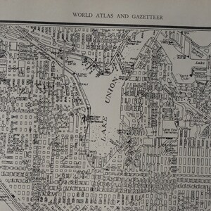 May include: A black and white map of a city with a lake labeled "Lake Union" and a stadium labeled "Stadium". The map also includes a canal labeled "Washington Canal" and a park labeled "Washington Park".