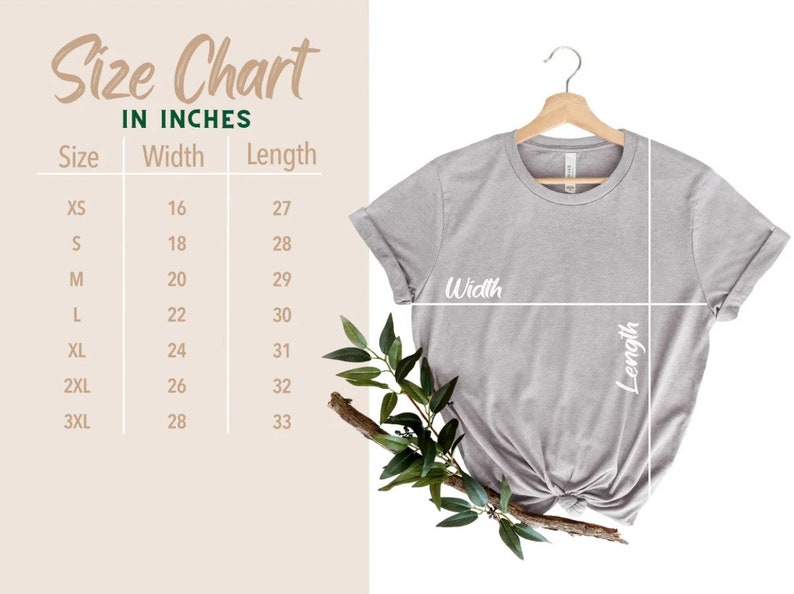 May include: A light gray t-shirt displayed on a wooden hanger, with a size chart in inches. The chart lists sizes XS to 3XL, with corresponding width and length measurements. Greenery accents the shirt.