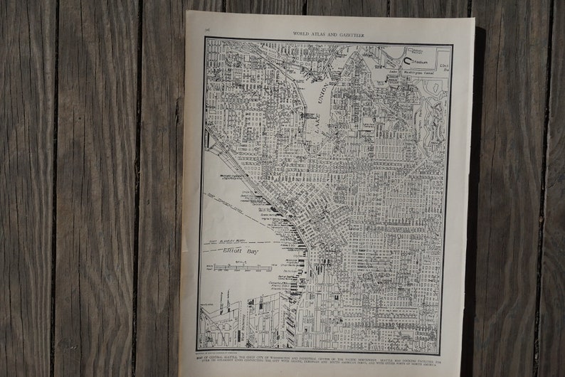 May include: Black and white map of Seattle, Washington, showing streets and bodies of water. The map is titled "World Atlas and Gazetteer".