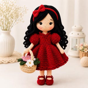 May include: A handcrafted crochet doll with long black hair, a red headband with a bow, and a red dress with puff sleeves. The doll has rosy cheeks and wears red shoes. It holds a small beige crochet basket filled with white and pink flowers.