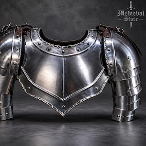 May include: A polished steel breastplate and pauldrons set featuring a central ridge, riveted edges, and brown leather straps. The armour includes articulated shoulder plates and a curved neckline, with the text Medieval Store visible in the corner.