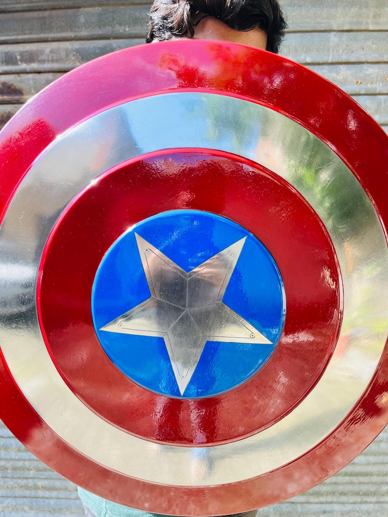 Pu&ograve; includere: Uno scudo rotondo con una combinazione di colori rosso, argento e blu. Lo scudo presenta cerchi concentrici rossi e argentati, con un centro blu contenente una stella argentata. &Egrave; probabilmente un oggetto di scena o da collezione.