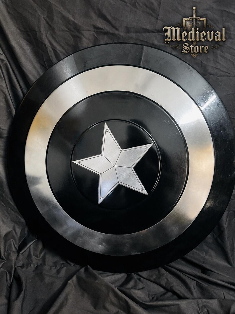 May include: A black and silver shield with a central silver star design. The shield has a circular shape with concentric rings of black and silver. The text "Medieval Store" is visible in the upper right corner.