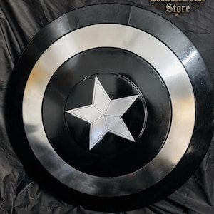 May include: A black and silver shield with a central silver star design. The shield has a circular shape with concentric rings of black and silver. The text "Medieval Store" is visible in the upper right corner.