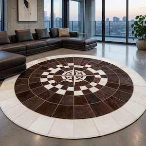 Può includere: Un grande tappeto circolare caratterizzato da un design centrale a rosa dei venti. Il tappeto è realizzato con pannelli di pelle bovina cuciti insieme in tonalità alternate di marrone scuro, marrone medio e crema, disposti in un motivo radiale geometrico.