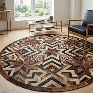 May include: A large circular area rug featuring a geometric patchwork pattern composed of cowhide panels in various shades of brown, black, tan, and cream. The design incorporates star-like motifs and chevron stripes arranged in a symmetrical layout.