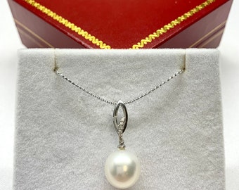 Puede incluir: Un collar con un colgante de perla blanca, una cadena de plata y un engaste con diamantes. El collar se muestra en una caja de terciopelo rojo con forro blanco.