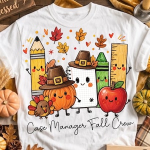 Puede incluir: Una camiseta blanca con un gráfico colorido de un lápiz, una calabaza con sombrero de peregrino, un cuaderno, un crayón verde, una regla, una manzana roja y un pavo. El texto "Case Manager Fall Crew" aparece en letra cursiva negra debajo.