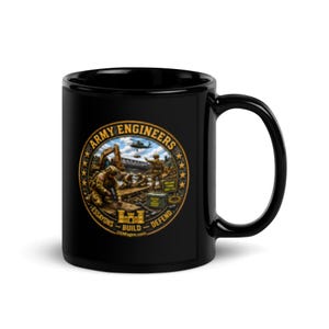 May include: A black ceramic mug featuring a circular graphic with the text ARMY ENGINEERS, ESSAYONS, BUILD, and DEFEND. The illustration depicts soldiers in camouflage uniforms working on a construction site with an excavator and a helicopter.