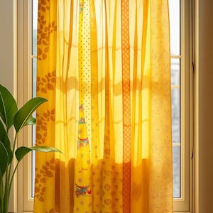 Puede incluir: Cortinas amarillas estampadas colgadas frente a una ventana. Las cortinas tienen varios diseños, incluyendo lunares, estampados florales y formas geométricas. La tela es transparente, permitiendo que la luz del sol se filtre.