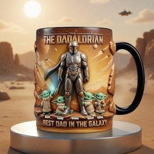 May include: A ceramic mug with a design inspired by The Mandalorian. The mug features the Mandalorian, Grogu, and the text "THE DADALORIAN" and "BEST DAD IN THE GALAXY". The handle is black, and the background shows a desert landscape.