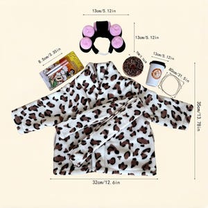 May include: A plush leopard print robe with a matching belt, a black headband with four pink hair rollers, a rectangular box with two pens, a chocolate donut, a white coffee cup with a brown logo, and a thin wire loop, all with labeled dimensions.