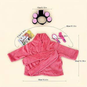 May include: A pink plush bathrobe with a matching belt, a black headband with five pink rollers, a small rectangular card with cartoon graphics, and two small pink plastic hair tools. Dimensions are marked as 13cm/5.12in, 8.5cm/3.35in, 11cm/4.33in, 80cm/31.5in, 35cm/13.78in, and 32cm/12.6in.