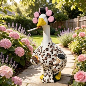 May include: A white goose figurine wearing a leopard print bathrobe, pink hair rollers, and holding a coffee cup and a donut. The goose has a yellow beak and is depicted with a cigarette in its mouth, standing amidst pink hydrangea flowers.