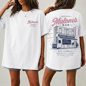May include: A white short-sleeve t-shirt featuring a small pink and blue logo on the front chest that reads Malone's Bar Off Campus. The back displays a large graphic of a building with the text Malone's Bar, Briar Nights, and Off Campus.